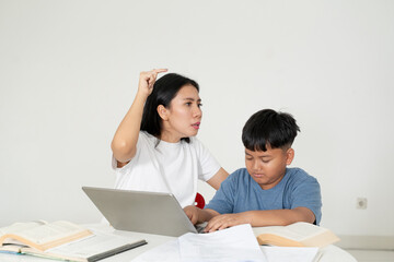 Obraz premium Angry Asian Mother Scolding Her Son While Studying with Laptop
