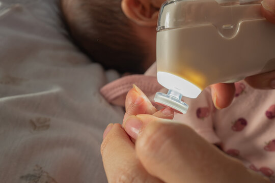Macro Shot of Mother Filing Newborn Baby's Nails with an Electric Trimmer