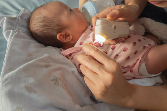 Mother Trimming Newborn Baby's Nails Using an Electric Nail Trimmer with LED Light