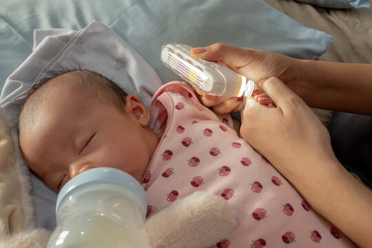 Mother Safely Trimming Sleeping Newborn Baby's Nails During Bottle Feeding