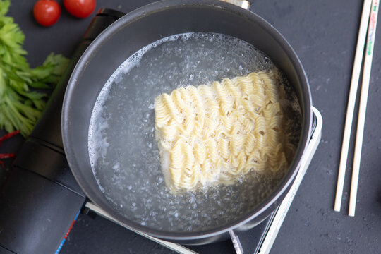 Boiling Instant Noodles Block in Pot on Portable Stove, Top View