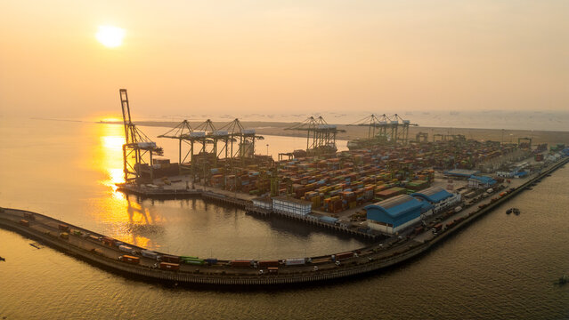 Aerial View of Container Port Terminal at Sunset with Cranes and Trucks