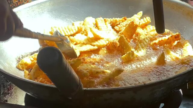 Deep frying crinkle cut potato fries in a wok