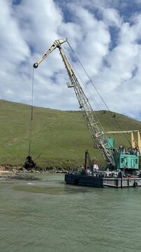 A large dredging barge with a crane operates on a river in Olkhonsky District, Irkutsk Oblast, Russia