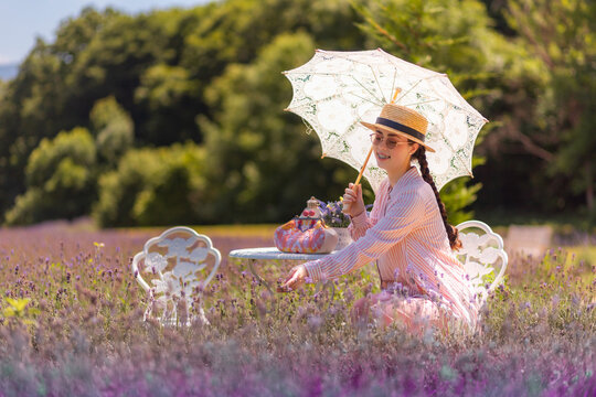 Caucasian woman in elegant outfit relaxes in lavender fields during French countryside vacation. Scenic nature and warm light enhance calm luxury mood.