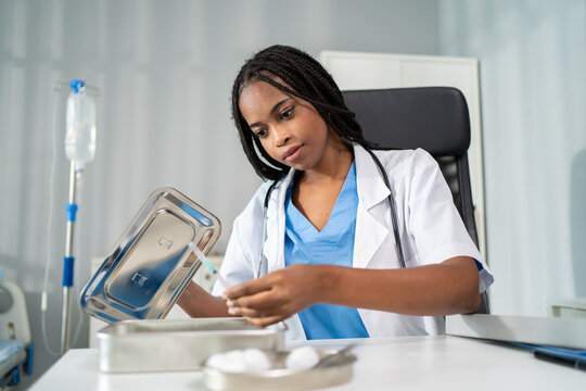 African female doctor holding medical supplies while working in doctor's office. 