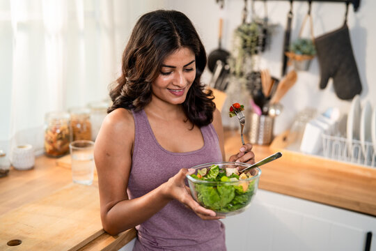 Attractive Indian woman preparing fresh vegetables in kitchen at home. 
