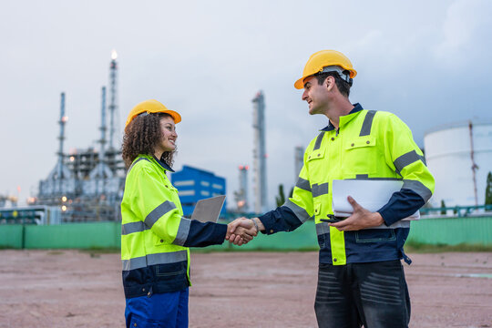 Caucasian male and Latina female engineers making handshake outdoors. 