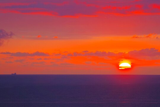 Dramatic purple and orange sunset over sea with cargo ship and text copy space
