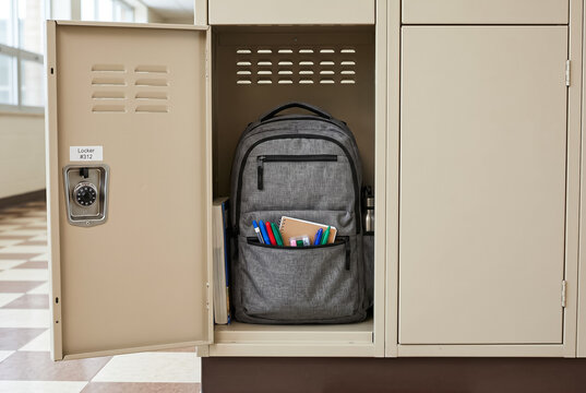 School backpack in beige metal locker with combination lock in hallway