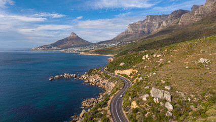 Scenic winding coastal road south of Camps Bay, South Africa, beneath a clear blue sky. Lion's Head and Camps Bay form a spectacular backdrop to one of Cape Town's most iconic coastal drives.