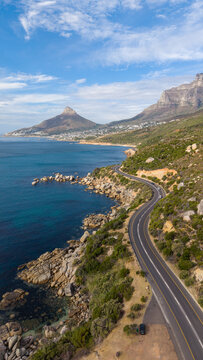 Scenic winding coastal road south of Camps Bay, South Africa, beneath a clear blue sky. Lion's Head and Camps Bay form a spectacular backdrop to one of Cape Town's most iconic coastal drives.