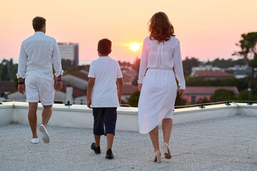 Obraz premium Family Walking On Rooftop Terrace At Sunset With Sea View Over Town