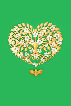 Gold heart tree shape, cherry blossom, bee ornament decoration on green background, Nature symbols with environmental conservation theme.