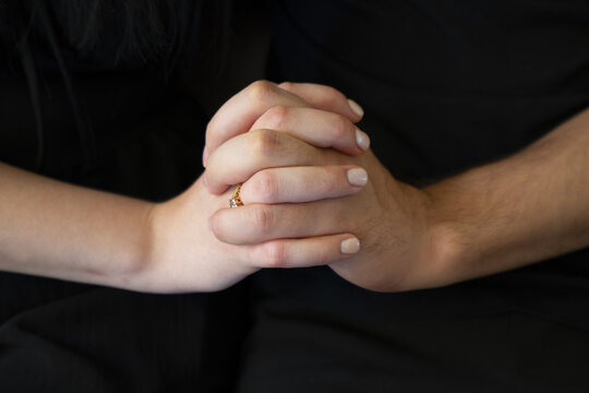 Close-up of a couple's hands clasped together, symbolizing love, connection, and partnership, highlighting details of their engagement ring.
