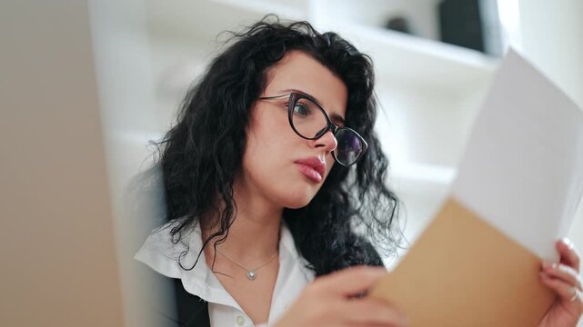 Shocked businesswoman reading negative news in a document, expressing surprise and concern. Corporate lifestyle, unexpected bad report or contract termination concept in modern office workspace
