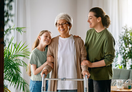 Happy Family Supporting Senior Woman with Walker at Home