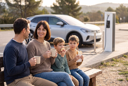 Family taking a break near electric car charging station during road trip