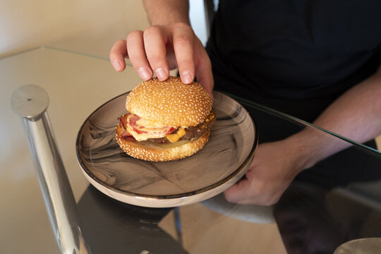 Freshly made hamburger with toppings on a plate, ready to enjoy, showcasing the deliciousness of fast food in a modern setting.