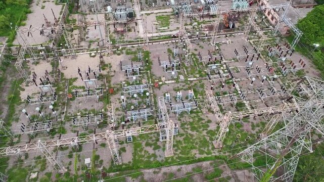 Drone shot of a large power distribution plant with transformers and transmission lines.