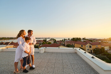 Obraz premium Family on Rooftop Balcony Overlooking Umag Seaview at Sunset Together on Terrace