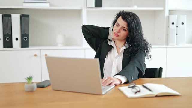 Businesswoman experiences intense neck pain during prolonged laptop work. Massages neck, conveying discomfort strain from desk work. Poor posture contributes to health issues and stress. Frustration