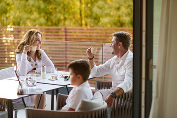 Obraz premium Family Enjoying Morning Coffee on Terrace Balcony While Relaxing and Conversing Together