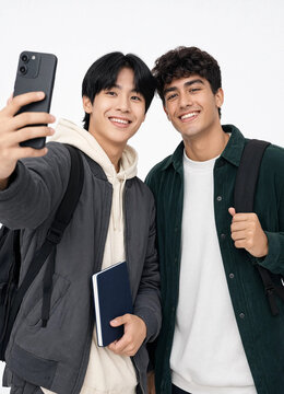 Smiling young male students taking selfie photo with smartphone on white background