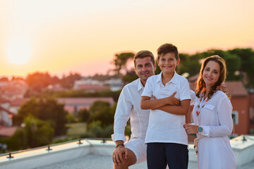 Obraz premium Smiling Family on Rooftop Terrace at Sunset Enjoying Coastal Vacation and Togetherness