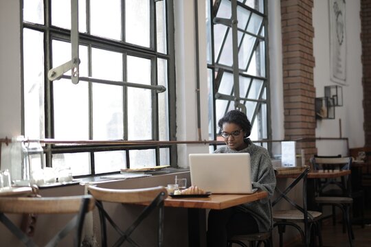 Young black woman works on laptop in cafe