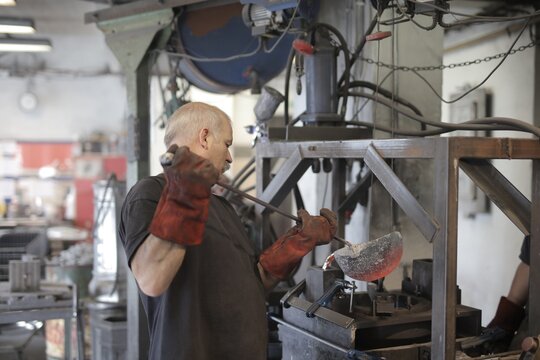 Foundry worker carefully pouring molten metal into a mold