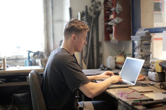 Young man working on a laptop in a workshop
