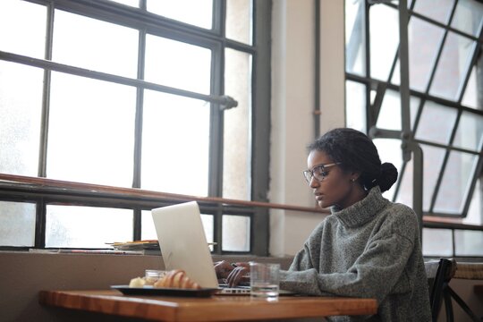 Focused woman working on laptop by a window