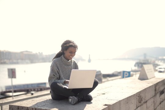 Happy woman works remotely on laptop outdoors