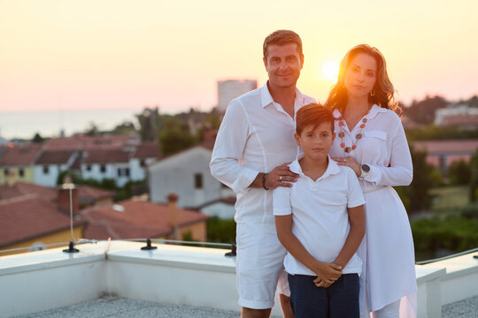 Family on Rooftop Balcony at Sunset With Sea View &mdash; Parents and Son Together