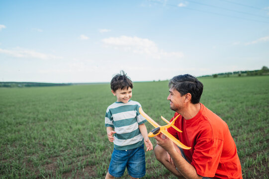 Father and son play with a toy airplane in the park