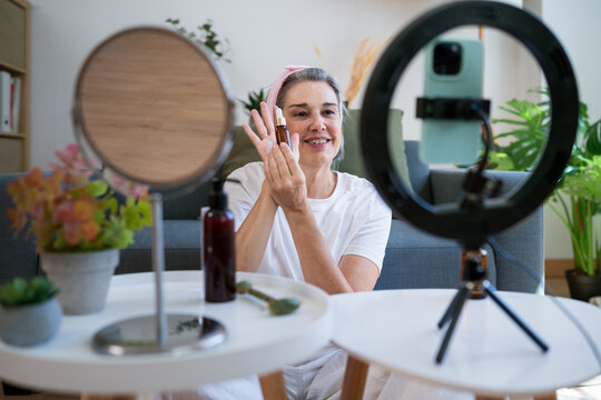 Woman demonstrating facial oil application for wellness content indoors