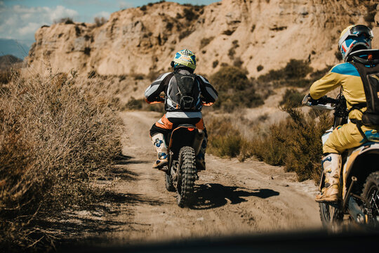Male biker with protective sportswear riding motorcycles on desert road