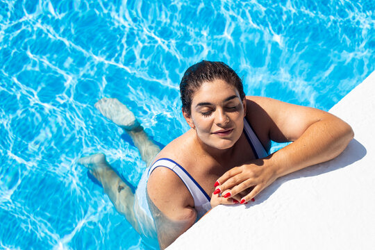 Portrait of content young woman relaxing at poolside in swimming pool
