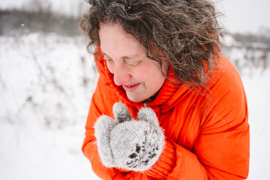 Mature woman shivering in snowfield wearing mittens