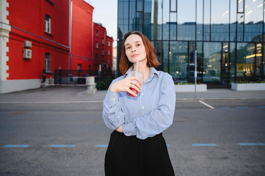 Confident businesswoman holds a refreshing drink outdoors in the city