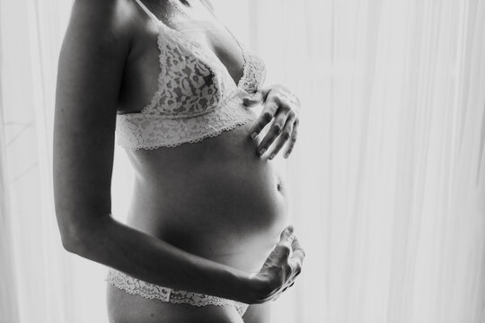 Expectant mother holding pregnant abdomen in lace lingerie