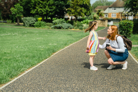 Mother talks to her young daughter on a path in an urban park