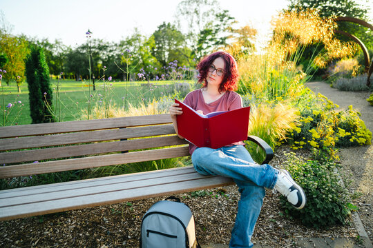 Teenage student studies with a red folder on an outdoor park bench