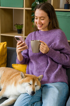 Woman enjoying relaxation time with dog and warm drink at home