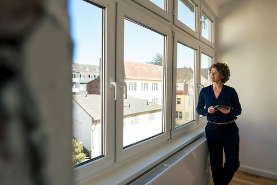 Real estate agent with tablet PC looking through window