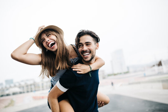 Spain, Barcelona, young man giving his girlfriend a piggyback ride