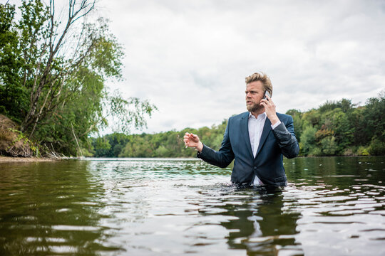 Businessman standing in a lake talking on the phone