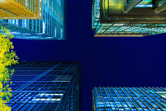 Futuristic cyber-blue city skyline of Tokyo's financial district from a dynamic looking-up perspective.
