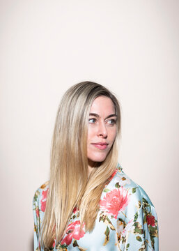 Serene woman in floral blouse looking away indoors with copy space